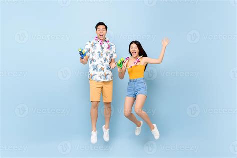 Young Asian couple in summer outfits with water guns jumping in studio ...