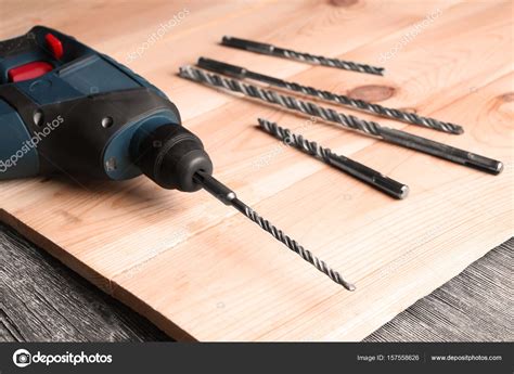 Drill, attachments and wooden board on table in carpenter's workshop ...