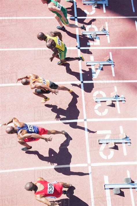 Sprinters taking off from starting blocks on track - Stock Photo - Dissolve