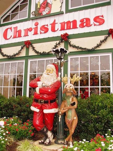 a statue of santa claus next to a lamp post in front of a christmas store