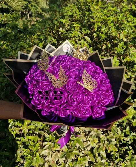 a bouquet of purple roses with butterflies on them is held by someone's arm