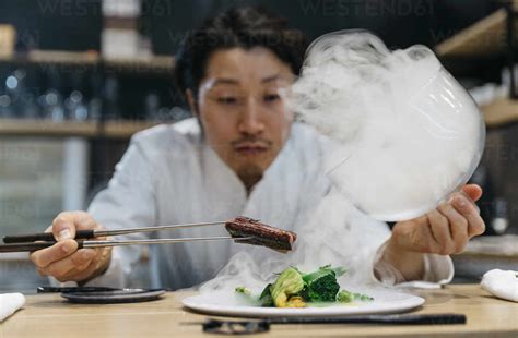 Chef cooking in restaurant with smoke dish stock photo