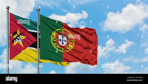 Mozambique and Portugal flag waving in the wind against white cloudy ...