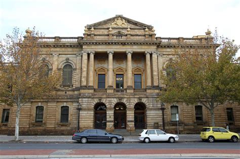 two cars parked in front of an old building with columns on the top and ...