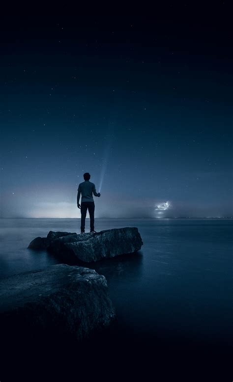 Man holding flashlight standing on rock photo – Free Sky Image on Unsplash