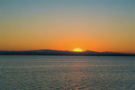 Clear sky. Sunset on the lake. Sun goes down behind the mountain ...