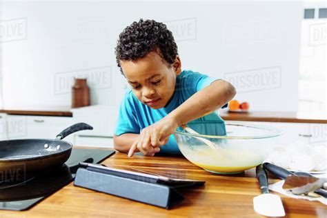 Mixed race boy cooking breakfast with digital tablet in kitchen - Stock ...