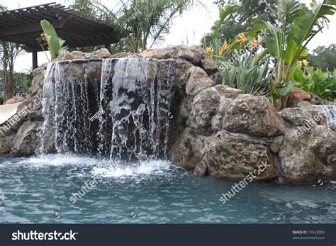 A Waterfall In To A Pool In A Luxury Backyard With Tropical Landscaping ...