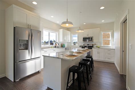 White l-shaped kitchen with shaker cabinets, engineered wood flooring ...