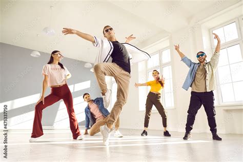 Group of people dancing in modern studio. Energetic male dancer with ...