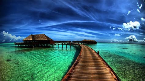 a long wooden dock extending into the ocean with a hut in the water on it