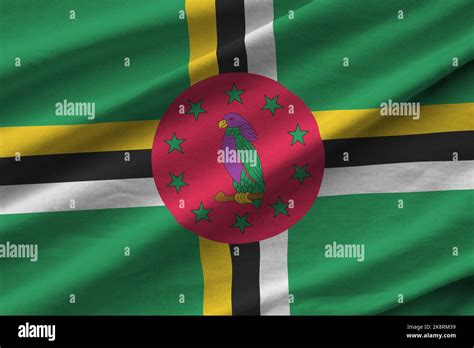 Dominica flag with big folds waving close up under the studio light ...