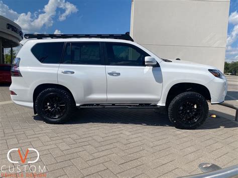 a white suv parked in front of a building with black rims on it's tires