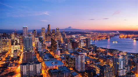 an aerial view of a city at night with the lights on and water in the ...