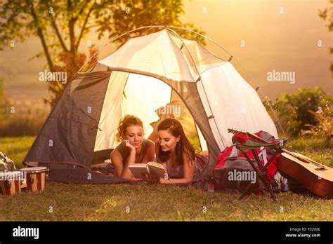 Two girls on camping trip lying in tent and reading book Stock Photo ...