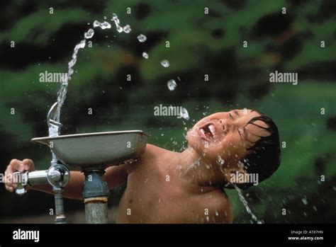 Young local boy drinking water from a fountain Stock Photo - Alamy