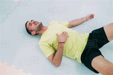 Exhausted man lying on floor on back - Stock Photo - Dissolve