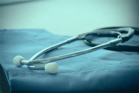 Stethoscope with blue doctor coat on wooden table with shallow DOF ...