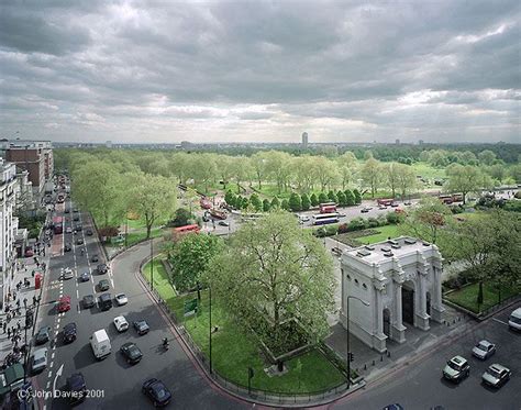 an aerial view of a city street with cars driving on the road and trees ...