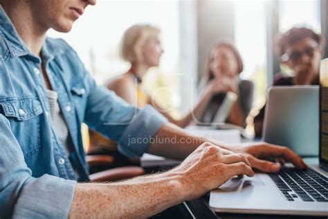 Young man using laptop with classmates studying in background – Jacob ...