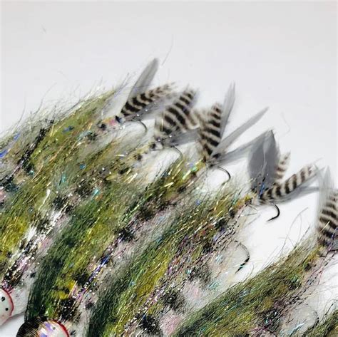 several fishing flies are lined up on a white surface with green and ...