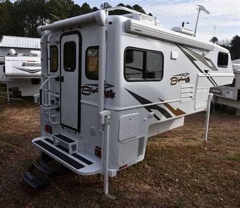 an rv parked in the grass next to other recreational vehicles