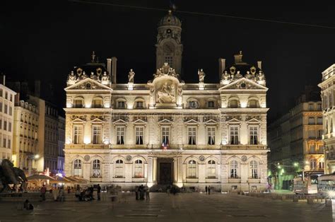 an old building lit up at night with people walking around