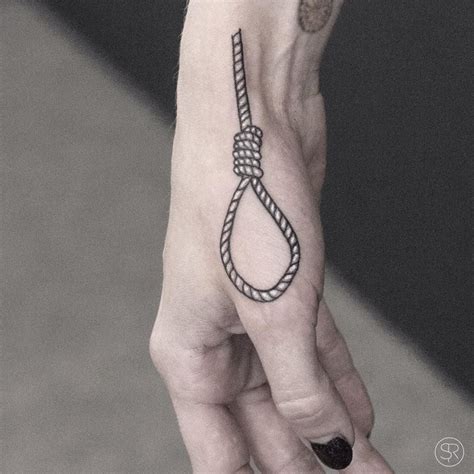 a person's hand with a tattoo on it holding up a rope that is attached ...