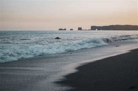 Premium Photo | A beach with a black sand beach and a large rock ...