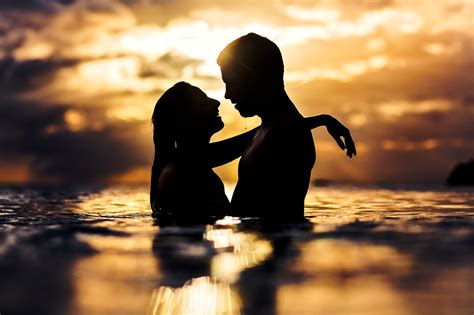 Sunset silhouette of couple kissing in water - photo by Two Mann Studios