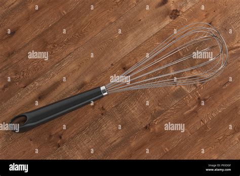 Wire whisk isolated on wood background. Include clipping path. 3d ...