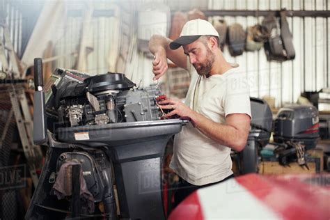 Man repairing outboard motor in boat repair workshop - Stock Photo ...