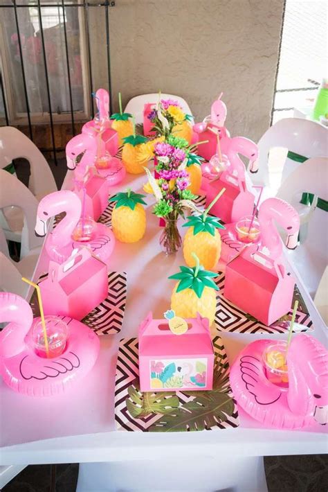 a table with pink flamingos, pineapples and oranges on it is set up for ...