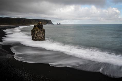 large rock on the black sand beach in vik, black beach at vik iceland ...