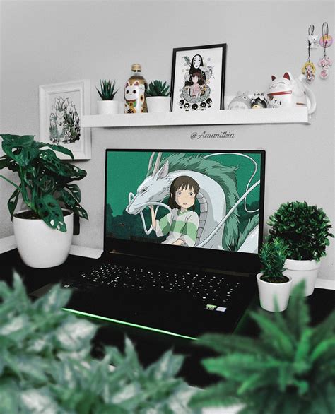 a laptop computer sitting on top of a desk next to a potted green plant