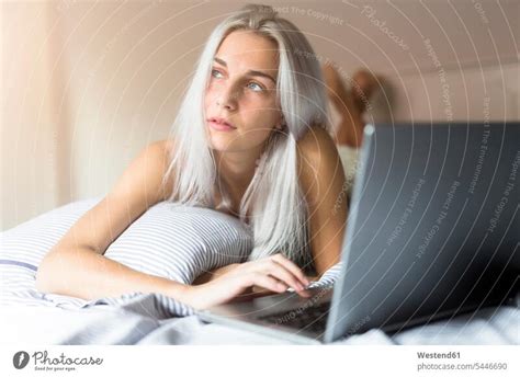 Young woman lying in bed using laptop - a Royalty Free Stock Photo from ...