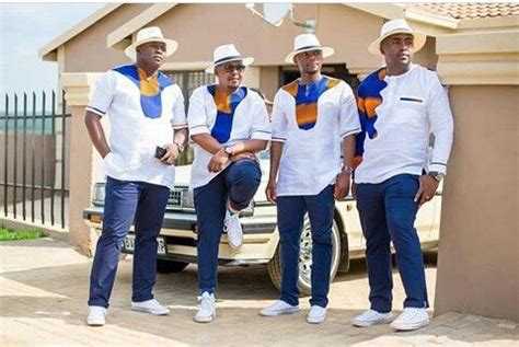 four men in white shirts and blue jeans standing next to a car