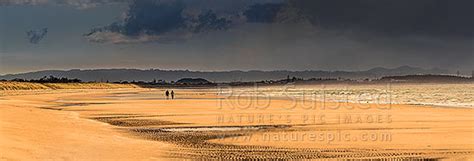 Beach walkers on Ruakaka Beach as the weather changes. Panorama ...