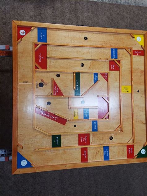 a wooden board game set up on top of carpeted floor with numbers and arrows