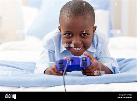 Smiling little boy playing video game lying on a bed Stock Photo - Alamy