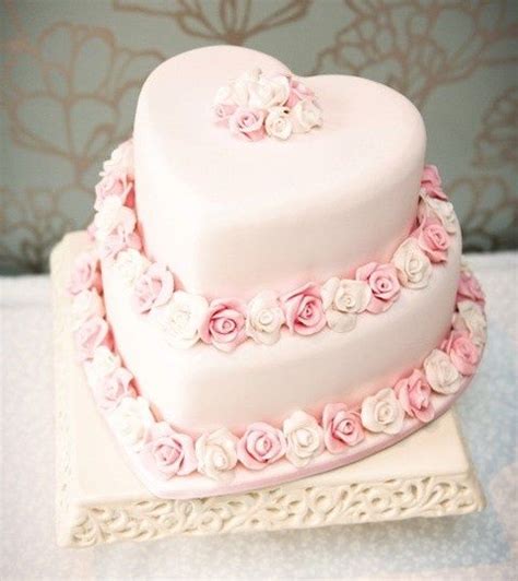 a white heart shaped cake with pink flowers on it