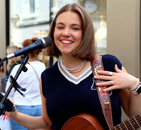 a woman holding a guitar and singing into a microphone