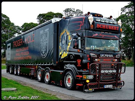 a large semi truck driving down a road next to lush green grass and ...