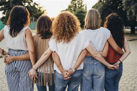 Group of women friends holding hands together against sunset ...