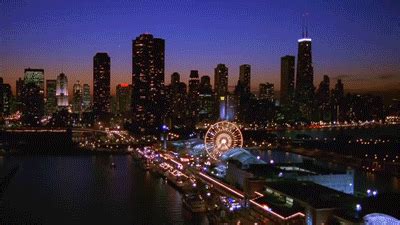 the city skyline is lit up at night with ferris wheel and lights in ...