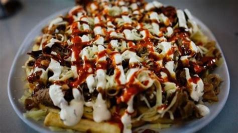 a white plate topped with french fries covered in cheese and sauce on ...