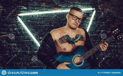 Tattooed Man Playing Guitar Near Illuminated Wall. Stylish Guy with ...