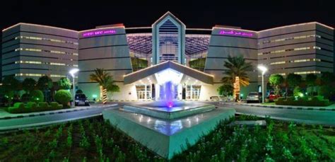 the hotel is lit up at night in front of its water fountain and lawn area