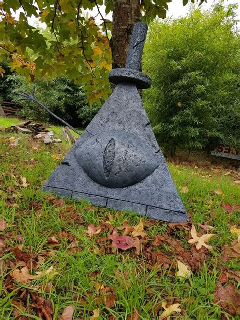 a stone sculpture in the grass near a tree with leaves around it and a ...