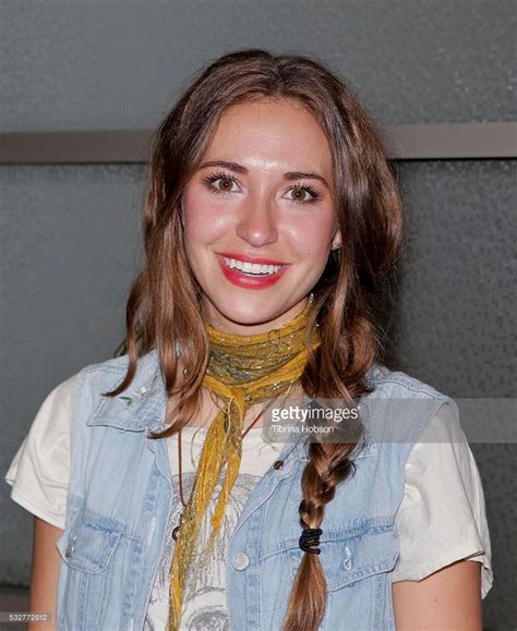 a woman with long hair wearing a blue shirt and yellow scarf smiles at ...